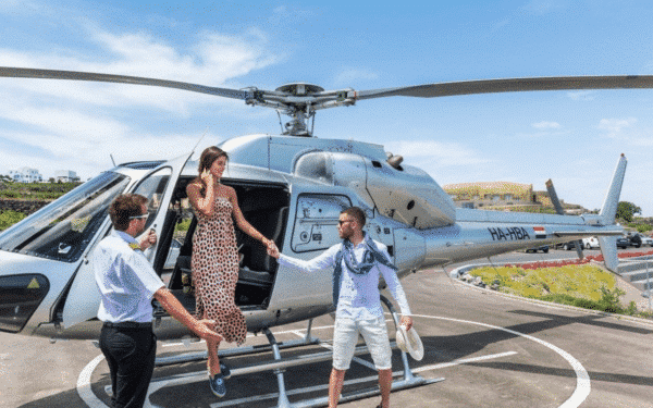 A couple stepping out of a helicopter while the pilot is holding the door for them