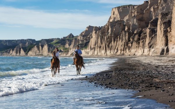 2 personas montando a caballo en la playa de Santorini