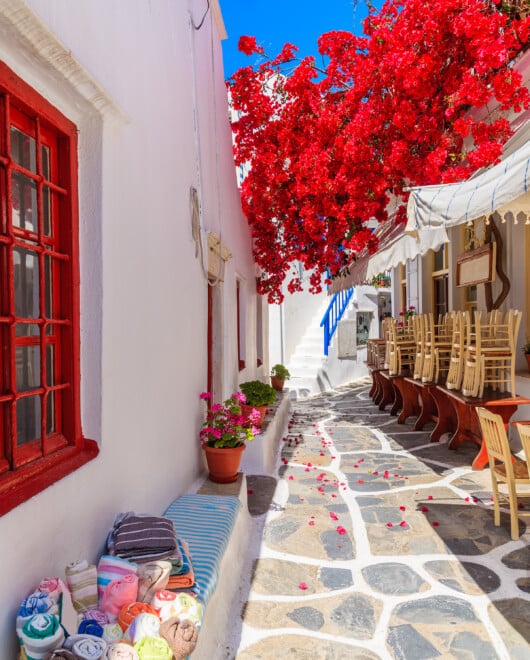 A,Narrow,Street,With,Flower,Decorated,Houses,In,Mykonos,Town,